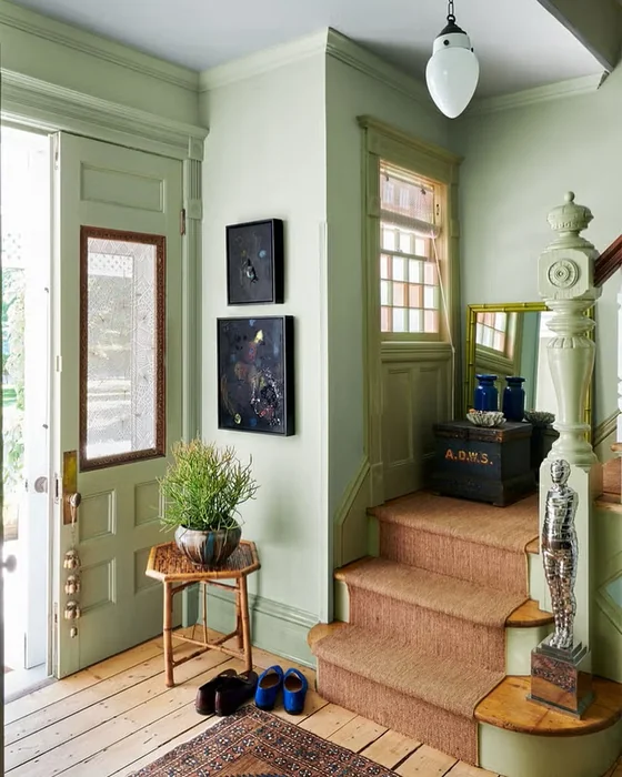 Sage Green Entryway with Stairs, Abstract Art, and Rattan Side Table
